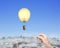 Woman hand pulling rope connected lightbulb hot air balloon