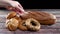 Woman hand put buns, bagels and cereals in glass jar next to rye organic bread on the table