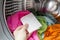 Woman hand put color absorbing sheet inside a washing machine.