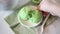 Woman hand put on a table plate with green ice cream. Mint or matcha ice cream.