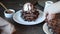 Woman hand put on the table plate with homemade chocolate waffles with ice cream decorated chocolate syrup.