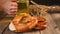 Woman hand put two glass of beer on the wooden table with freshly baked homemade salt Bavarian pretzel. German bakery.