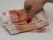 A woman hand puts a bundle of five-thousandth banknotes on the surface, purchases are made, background