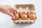 Woman hand selected egg in egg carton on white background