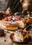 Woman hand sprinkles icing sugar on a cheesecake with berries on rustic wooden table with samovar and teapot, complex composition