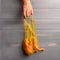 Woman hand takes eco friendly string bag with ugly carrot. Copy space