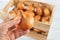 Woman hand takes one raw yellow onion from wooden crate. Fresh onion in a wood box. Eco-friendly rustic style containers for