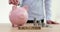 Woman hand throws money coins into piggy bank, word savings