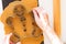 Woman hand utting out gingerbread man on raw dough using metal form of gingerbread man on black teflon baking sheet on the white