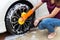 Woman hand wearing orange gloves with yellow sponge washing wheel modern car or cleaning automobile.