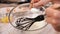 Woman hand whisk egg whites in a glass bowl - close-up