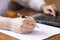 Woman hand writing a contract with a laptop beside