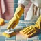 woman hand in yellow glove is cleaning tiled white surface in bathroom