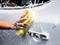 Woman hand with yellow sponge washing car