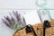 Woman handbag with lavender flower and blank paper notepad on rustic blue wooden desk. Flat lay, top view, overhead. Summer