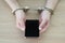 Woman in handcuffs holds modern smartphone sitting at table