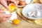 Woman hands breaking an egg to separate egg white and yolks, egg