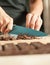 Woman hands chopping chocolate block for celebratory cake