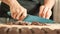 Woman hands chopping chocolate block for celebratory cake