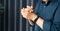 Woman with hands clasped praying while sitting at desk in office. Businesswoman praying at work. Contemplative prayer thinking in