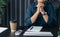 Woman with hands clasped praying while sitting at desk in office. Businesswoman praying at work. Contemplative prayer thinking in