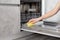 Woman hands cleaning dishwasher panel with yellow rag in kitchen. Close up.