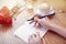 Woman hands close-up writing in notebook, using pencil, blank pages for layout. Cappuccino latte coffee with heart on top. Flowers