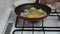 Woman hands cooking scrambled eggs with white onion.