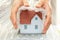 Woman hands covering a model house with bubble wrap- house protection or insurance concept