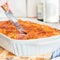 Woman hands cuting meat lasagna in the form of baking. Italian food