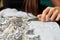 Woman hands cutting away loose ends of threads from fabric with machine embroidery using scissors.