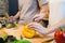 Woman hands cutting bell pepper in the kitchen. Beautiful happy asian couple are cooking in the kitchen.