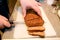 Woman hands cutting piece of meatloaf, she prepare for tasting of food at kitchen. Chef cutting meatloaf with knife on board.