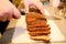 Woman hands cutting piece of meatloaf, she prepare for tasting of food at kitchen. Chef cutting meatloaf with knife on board.