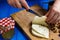 Woman hands cutting spicy homemade cheese on cutting board, serv