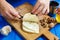 Woman hands cutting spicy homemade cheese on cutting board, serv