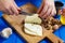 Woman hands cutting spicy homemade cheese on cutting board, serv