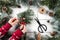 Woman hands decorates a Christmas gift with fir branches on wooden background with scissors and skein of jute.