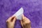 Woman hands folding paper triangle to make smaller triangle on the violet surface