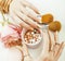 Woman hands with golden manicure and many rings holding brushes, makeup artist stuff stylish, pure close up pink flower