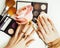 woman hands with golden manicure and many rings holding brushes, makeup artist stuff stylish, pure close up pink perfect