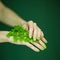 Woman hands with green nail polish holding some tropical leaves