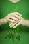 Woman hands with green nail polish holding some tropical leaves