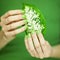 Woman hands with green nail polish holding some tropical leaves