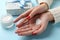 Woman hands, heart shape created from winter cream, jar of winter cream for skin on blue background