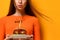 Woman hands hold big burger barbeque sandwich with beef and lit candle for birthday party on yellow