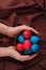 Woman hands hold full of easter eggs clay bowl on brown cloth background. concept of holiday mood.Top view