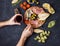 Woman hands hold a glass of wine. Appetizer, italian antipasto, ham, olives, cheese, bread, grapes, pear on dark stone background.