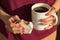 Woman hands holding breakfast coffee and alfajor with cream dulce de leche and powdered sugar. Selective focus and blur background