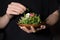 Woman hands holding clay plate full of fresh sunflower microgreens sprouts decorated with flowers